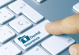A person preparing to touch a button that reads “Dental Insurance” on a computer keyboard