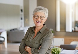 Senior woman with glasses smiling with arms folded