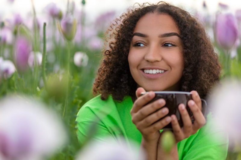 Woman smiling and drinking tea or coffee.