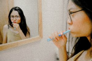 Woman looking in mirror to brush her teeth