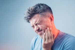 a man experiencing face pain due to a dental emergency